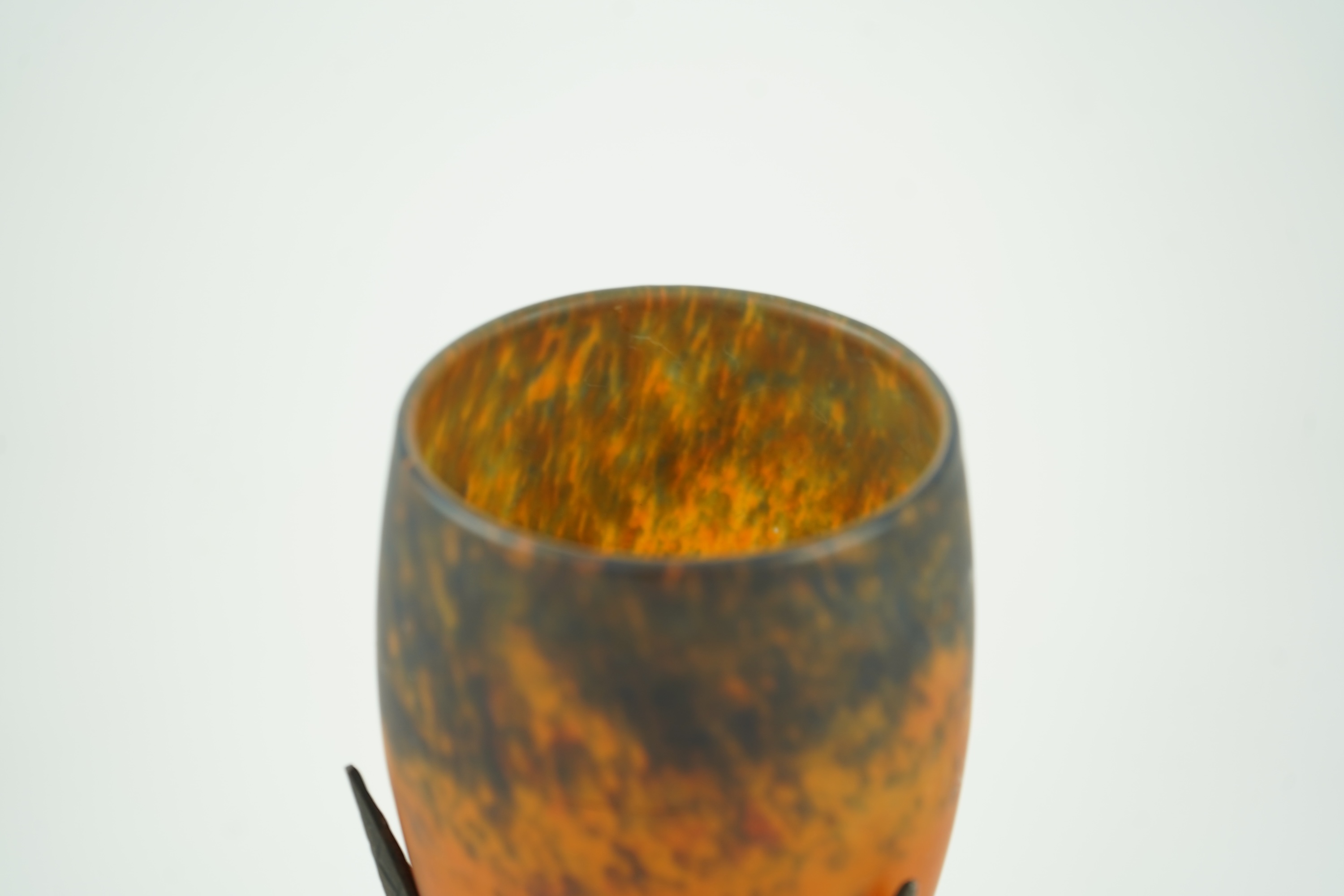 Manner of Muller Freres and Robj: A French Art Deco table lamp the mottled orange glass shade supported by naturalistic palm-leaf metal supports terminating in a circular hammered metal base, 40cm high